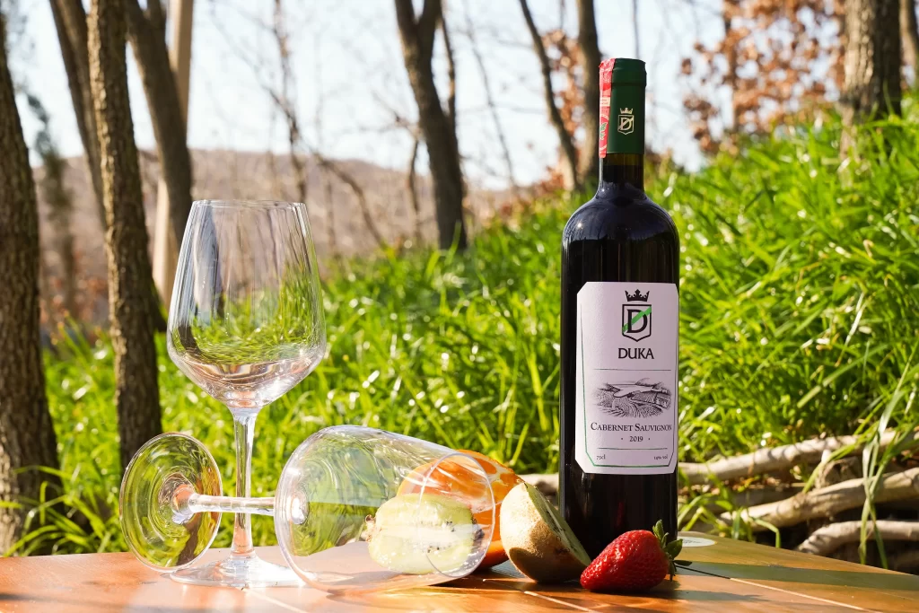A bottle of 'Cabernet Sauvignon' with a backdrop of DUKA Winery & Vineyard